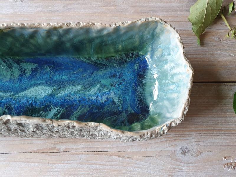 Decorative ceramic dish with blue and green glaze on a wooden surface