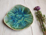 Green ceramic plate with a floral arrangement on a wooden surface