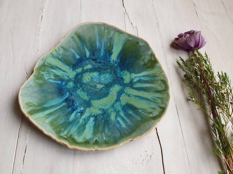 Green ceramic plate with a floral arrangement on a wooden surface